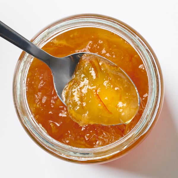 Jar of VAGGSÅNG orange elderflower spread, bright orange colour, glass jar with a spoon.