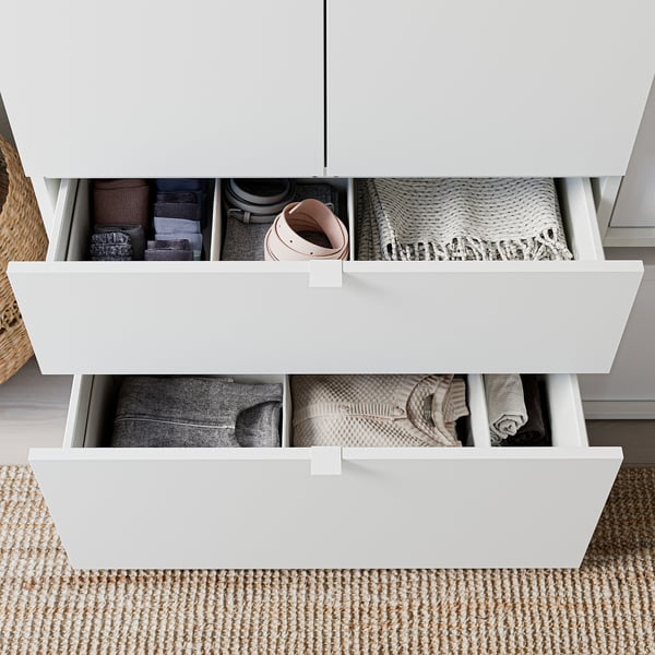 Neatly organised drawer units with clothes; light wood, rectangular, minimalist design.