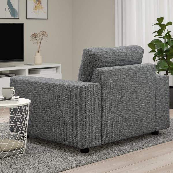 A room with a grey VIMLE armchair on a shaggy rug, beside a small table with a coffee mug.