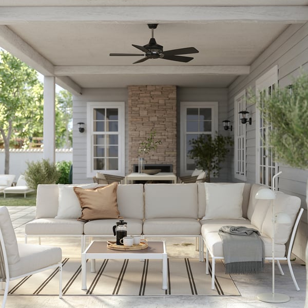 Moderní venkovní terasa s bílým nábytkem, stropním ventilátorem, pruhovaným kobercem a konferenčním stolkem.