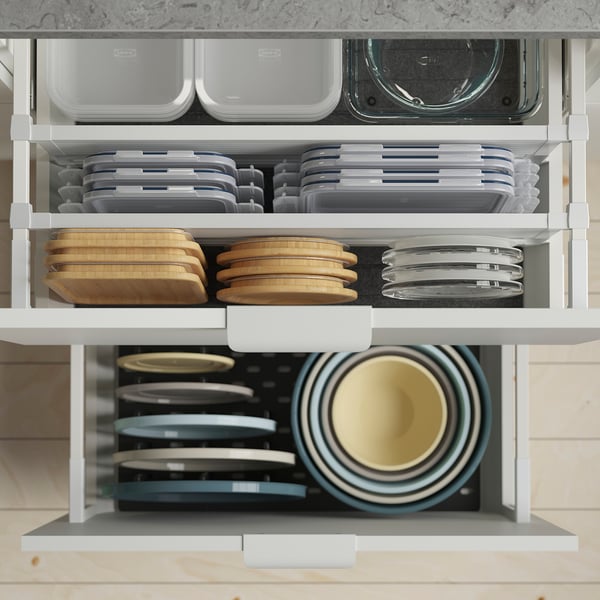 Kuchyňská zásuvka Ikea s dózami na potraviny, prkénky a miskami.