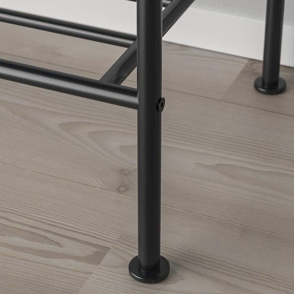 Detailní záběr na robustní kovovou nohu stolu na dřevěné podlaze, která ukazuje industriální design a kvalitní konstrukci.