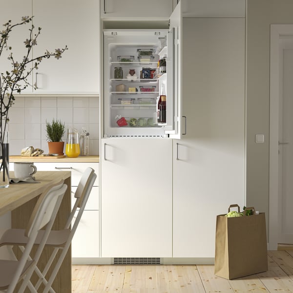Otevřená moderní lednice v kuchyni s nastavitelnými skleněnými policemi a LED osvětlením, které zdůrazňuje její organizované a průhledné skladování.