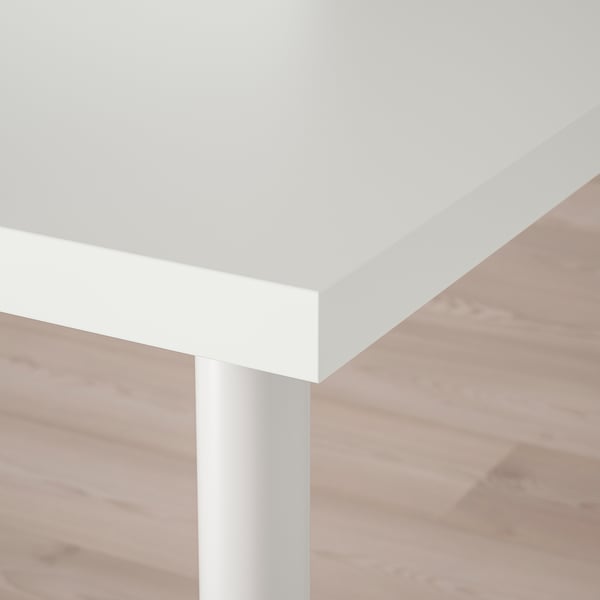 Detailní záběr na moderní bílou stolní desku s elegantním okrajem a kovovou nohou, která předvádí čistý design a pevnou oporu.