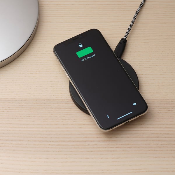 Smartphone se bezdrátově nabíjí na podložce. Displej zobrazuje 97% nabití.
