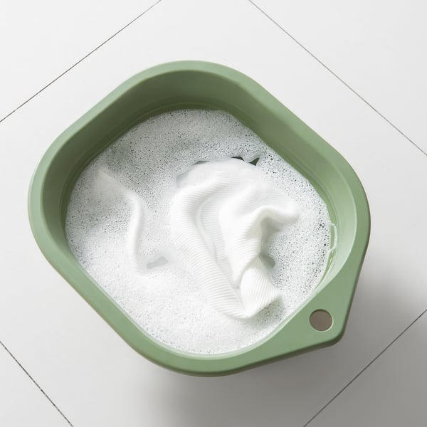 Skládací zelená vana s bílým oblečením, ideální na mytí rukou a čištění mopů.