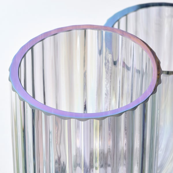 Vedle sebe stojí dvě barevné válcovité vázy s texturovanými, reflexními povrchy, které předvádějí svůj elegantní a hravý design.
