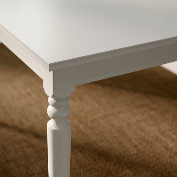 Kvalitní bílý rozkládací stůl se soustruženými nohami a hladkým povrchem.