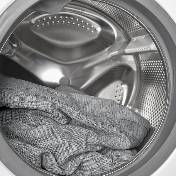 Buben pračky s šedým oblečením, který zdůrazňuje funkci snadného čištění.