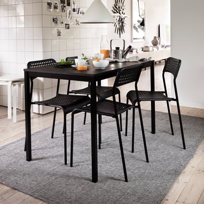 Moderní kuchyňská linka s černou jídelní soupravou, jídlo, bílý backsplash, šedý koberec.