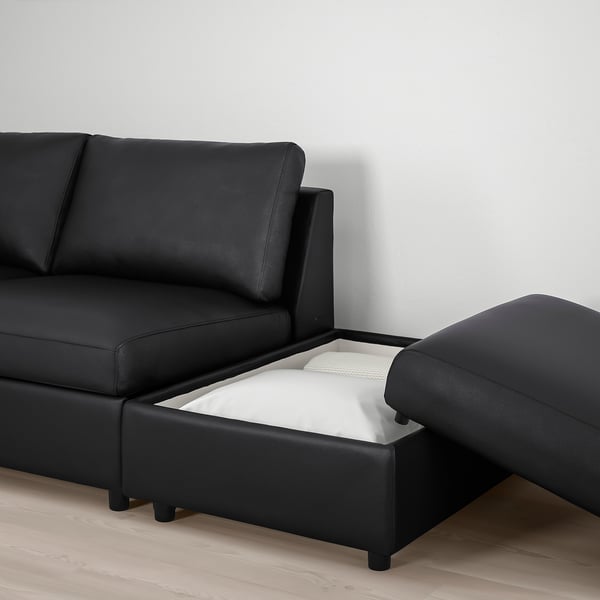 Černá pohovka s oboustranným lenoškou, která má skrytý úložný prostor pod sedákem, ideální pro organizaci předmětů.