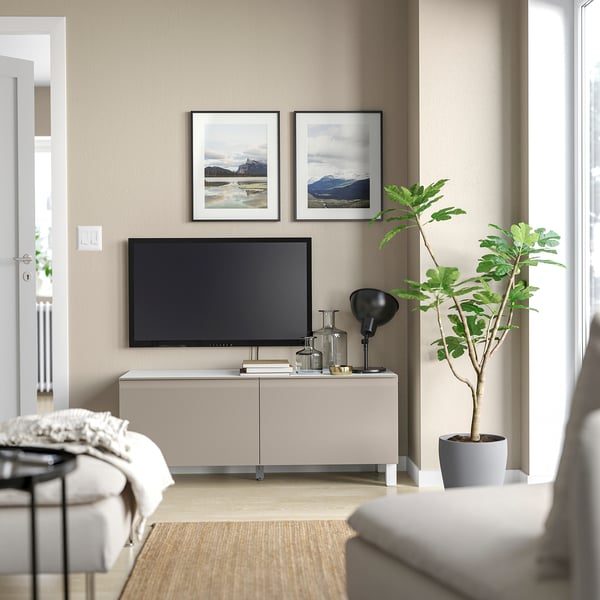 Modern living room with beige BESTÅ tv stand, flat screen tv, potted plant, and framed nature photos.