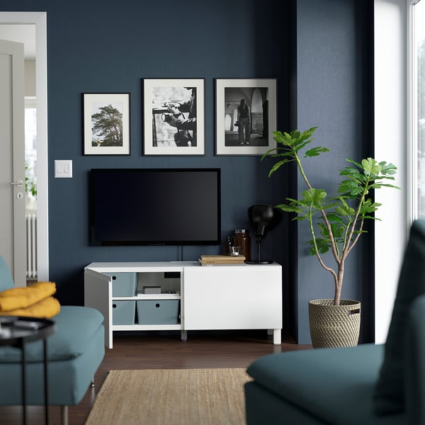 Modern living room with BESTÅ tv stand, adjustable shelves, soft-close doors, flat-screen tv, turquoise seating, and plant.