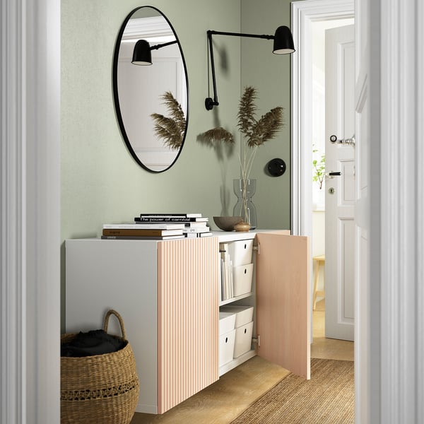 A modern entryway with a white BESTÅ storage unit, featuring open and closed compartments, adjustable shelves, and wall-mounted lights.