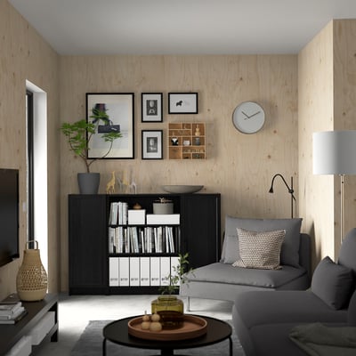 Minimalist living room with BILLY bookcase, grey sofa, wooden walls, and decorations.