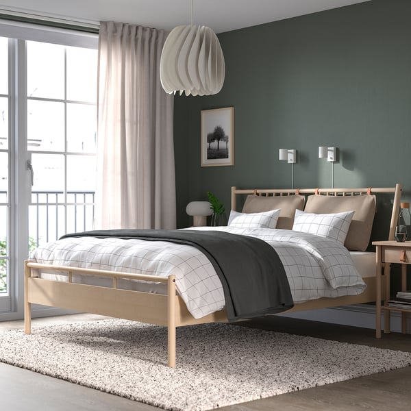 Bed with privacy shades, unique lamp, grey/tan bedding, dark green wall with lights.