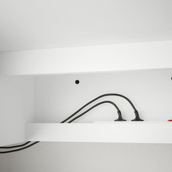 Black cables curve over white desk, illustrating integrated cable management.