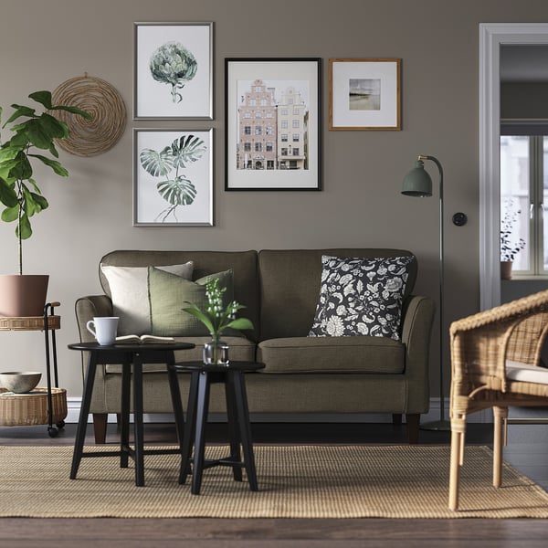 Olive sofa, botanical art, wicker chair, side table with mug and plant.