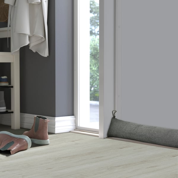 Small trainers by door with draught stopper, clothes, basket.
