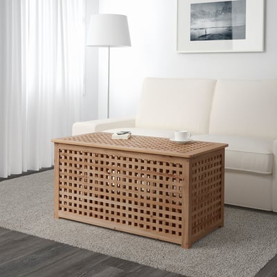 Wooden lattice coffee table with storage sits near a white sofa. It HOLds a mug and remote, offering practical storage space.