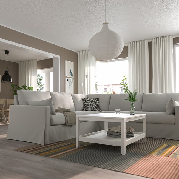 L-shaped sectional sofa in bright room with rug, coffee table, & windows.