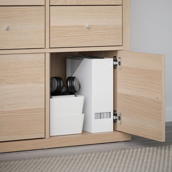 Light wood cabinet open with KALLAX shelves and white storage bins, showing home organisation.