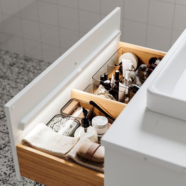 Well-organized bathroom drawer with tidy compartments, lights, and various toiletries.