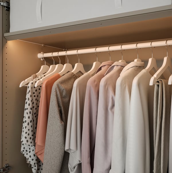 A wardrobe with built-in led lights illuminating clothes on hangers, highlighting the interior for easy selection.
