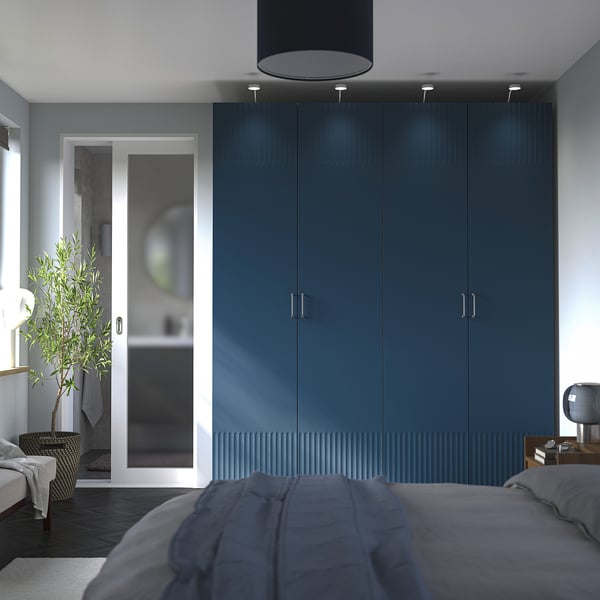 Modern bedroom with large blue PAX wardrobe, grey bedding, glass door, and plant.