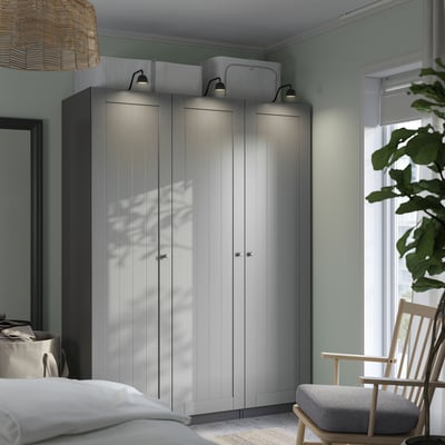 Modern bedroom with tall PAX wardrobe, plant, and window.