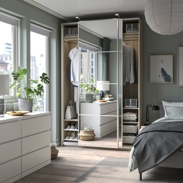 Modern bedroom with PAX wardrobe, plants, and city view.