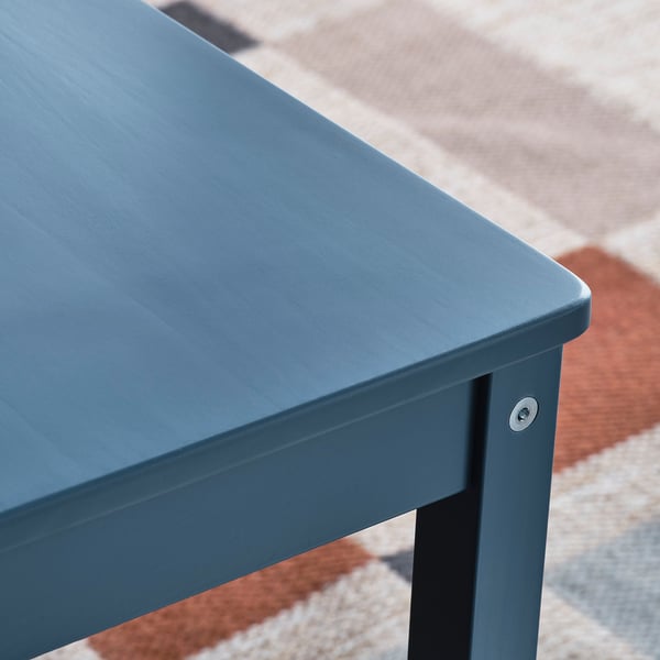 Close-up of a blue wooden tables corner, showing smooth, fine-grained surface and sturdy joints.