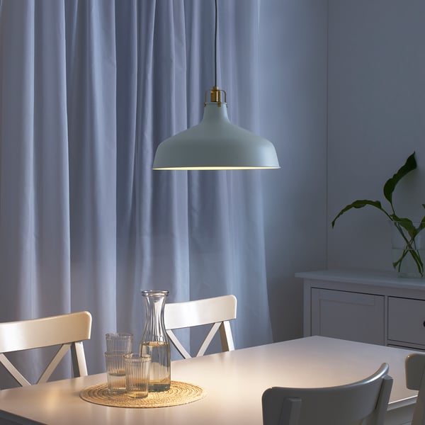 Modern dining area with RANARP lamp, table, chairs, and glassware. Soft lighting creates cosy atmosphere.