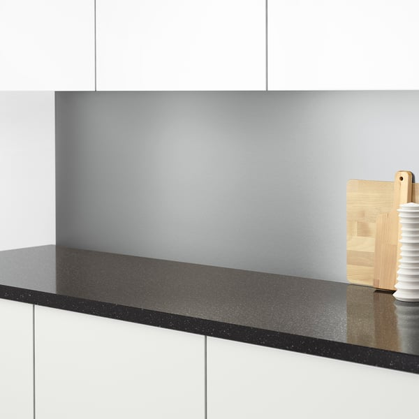 Modern kitchen counter with sleek black speckled surface, light grey backsplash, wooden utensils.