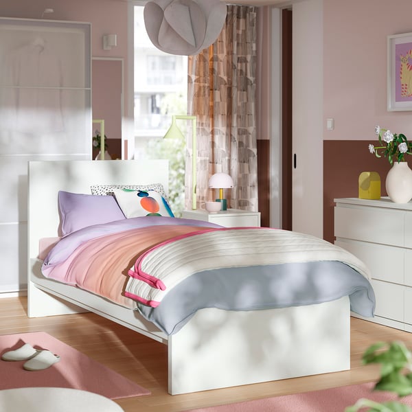 White STORKLINTA bed with colourful bedding in minimalist room