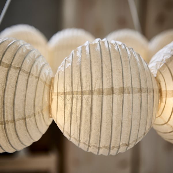 A close-up of soft white paper lanterns hanging in a row, showcasing their textured, ribbed design for ambient lighting.