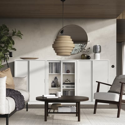 Modern living room with white TONSTAD cabinet, round table, wooden chairs, green plant, and hanging light fixture.