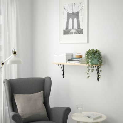 Cosy corner with grey armchair, side table, books, plant, brooklyn bridge print.