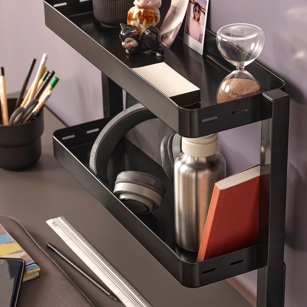 Desk organiser shelf holding headphones, water bottle, and notebook.