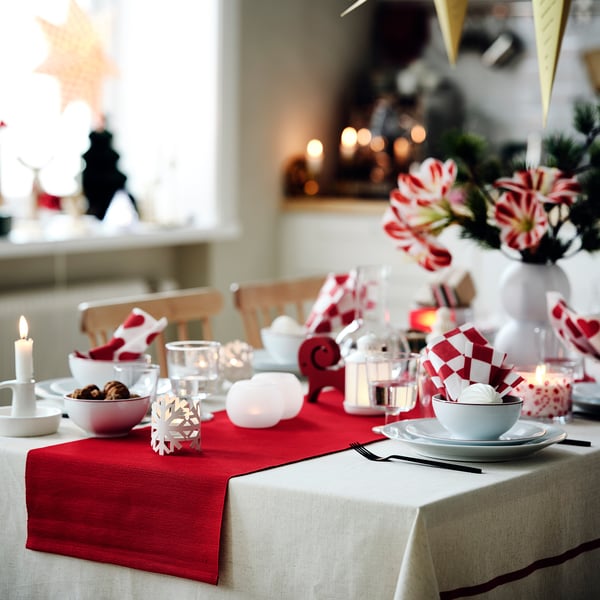 Christmas table set with red checked napkins, candles, and decorations.