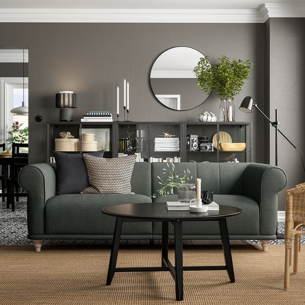 Modern living room with VISKAFORS green sofa, round black coffee table, grey walls, and stylish decor.