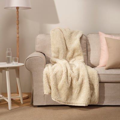 ÅSJORDFLY cremefarbener Überwurf auf beigem Sofa, recyceltes Polyester, weich, sorgt für Wärme.