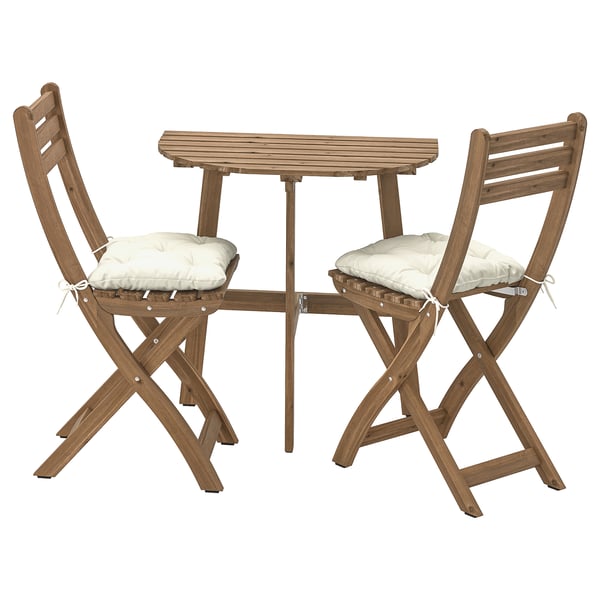 Ein ASKHOLMEN Outdoor-Möbelset bestehend aus einem quadratischen Tisch und zwei Klappstühlen mit beigen Kissen, alle aus Akazienholz.