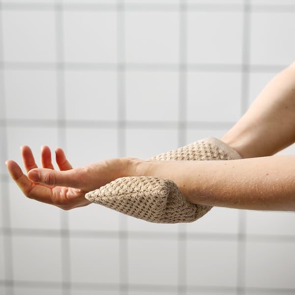 Die Person verwendet den GULVIAL-Scheuersauger an der Hand und demonstriert seine Peeling-Finger an einer gefliesten Wand.
