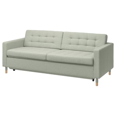 Hellgrünes Sofa mit Holzbeinen, quadratischen Kissen und modernem Design.