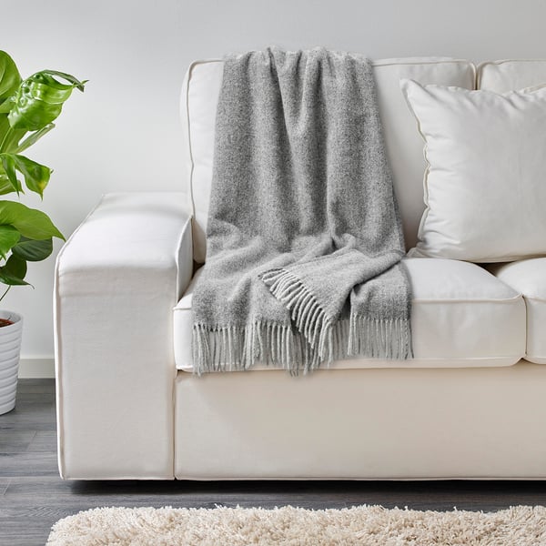 Graue Wolldecke auf weißer Couch, die kuschelige Wärme und weichen Griff bietet.