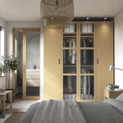 Modernes Schlafzimmer mit PAX-Kleiderschrank, Glastüren, blauem Bett und Pendelleuchte.