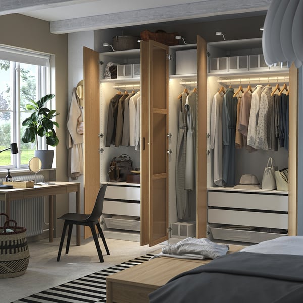 Moderner begehbarer Kleiderschrank mit offenen Türen, in dem Kleidung auf Kleiderbügeln, Regalen und Schubladen präsentiert wird, mit verstellbaren Füßen und integrierter Beleuchtung.