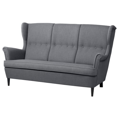 Ein graues IKEA STRANDMON 3-Sitzer-Sofa mit hohen, geflügelten Rückenlehnen, geknöpften Kissen und dunklen Holzbeinen.