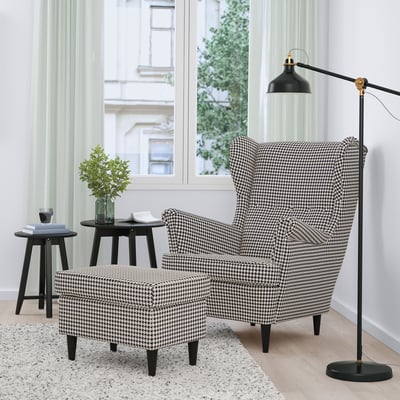 Gemütlicher Hahnentritt-STRANDMON-Stuhl und Ottomane am Fenster, mit Lampe, Vase und Büchern.